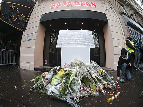 A man kneels next to a commemorative plaque reading "In memory of the injured and killed victims of the attacks of November 13, 2015 - to the 90 lives taken" in front of the Bataclan concert hall in Paris on November 13, 2016