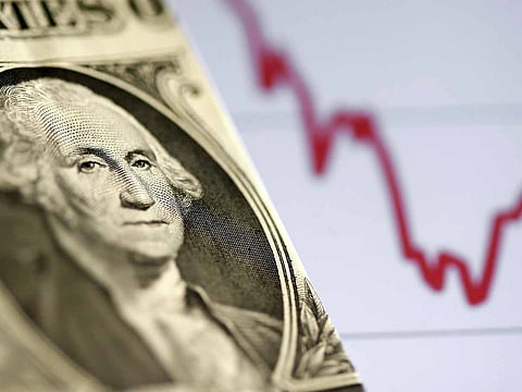 A US dollar note is seen in front of a stock graph. The dollar is facing renewed questions about its status as the globe's primary reserve currency.