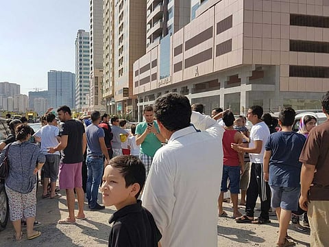 Residents outside a building on fire in Sharjah.
