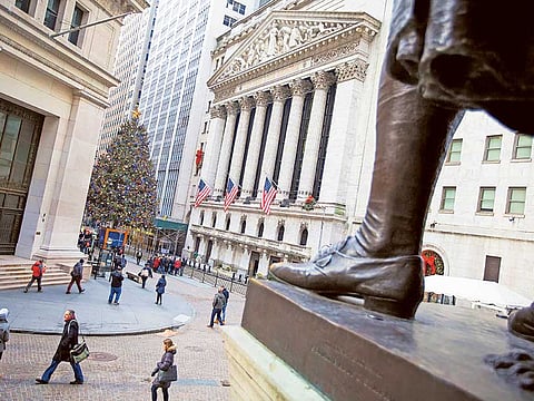 Pedestrians walk along Wall Street as a Christmas tree stands in front of the New York Stock Exchange in New York.