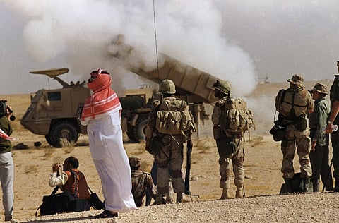 A Saudi Arabian official and Saudi soldiers watch a multiple rocket launch system near the Kuwaiti border in Saudi Arabia in a 1990 file picture.