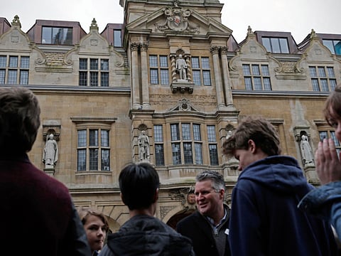 People stop to look at a statue of British businessman Cecil Rhodes on the facade of Oriel College in Oxford.