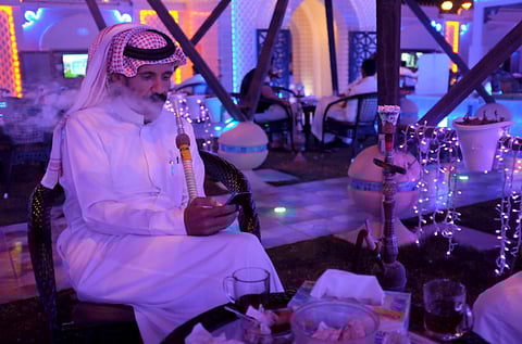 FILE PICTURE: A Saudi man uses his smartphone as he smokes shisha at a cafe in Dammam, Saudi Arabia.