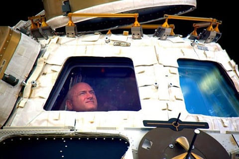 Astronaut Scott Kelly looks out the cupola of the International Space Station