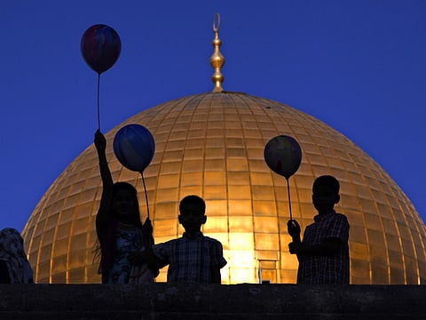 Palestinian children hold balloons near the Dome of the Rock Mosque in the Al Aqsa Mosque compound in Jerusalem's Old City.