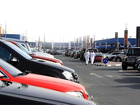 Men walk past used cars at the Al Aweer car market.