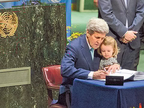 US Secretary of State John Kerry holds his granddaughter as he signs the Paris Agreement on climate change on April 22, 2016 at the UN headquarters.