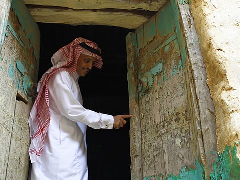 A man shows the door of a traditional old building in Asir Province, Saudi Arabia.