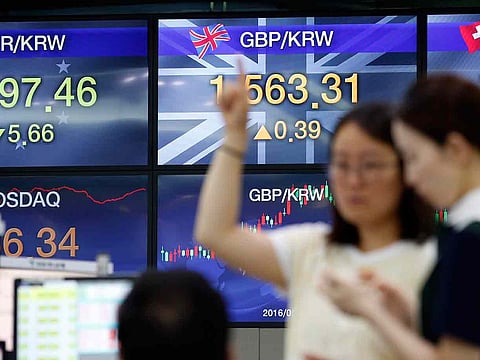File photo: Currency traders talk during a lunch break near screens showing the foreign exchange rates between the Pound and the South Korean Won currencies at the foreign exchange dealing room in Seoul, South Korea