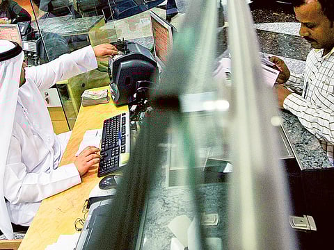 A teller at a bank in Dubai. How can you ensure not defaulting on loans after losing your job? Let's find out! Picture used for illustrative purposes only.