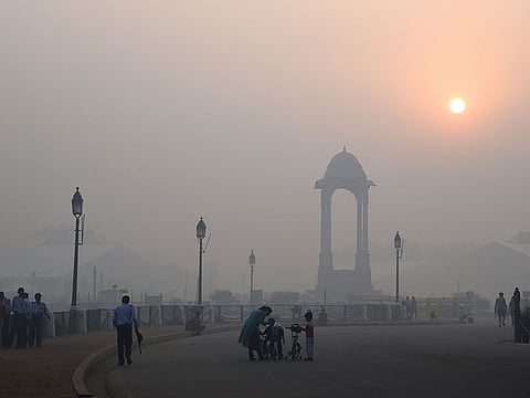 Pedestrians walking near the India Gate monument amid heavy pollution in New Delhi
