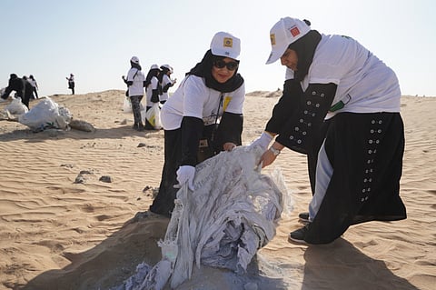 Volunteers removing plastic from a sandy area as part of a previous Clean Up UAE campaign.