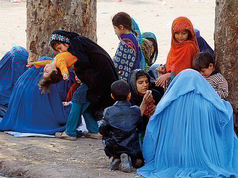 Afghan refugee families sit outside the government registration office preparing to leave for their homeland, in Peshawar, Pakistan.
