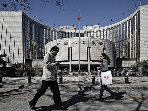 Pedestrians walk past the People's Bank of China (PBOC) headquarters in Beijing, China. Chinese small-cap stocks rallied after Premier Li Keqiang failed to mention a planned shift to a more market-based system for initial public offerings, a reform seen luring funds from existing equities.