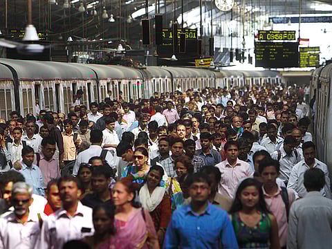 Commuters disembark from trains at a train station in Mumbai.
