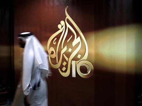 In this Wednesday Nov. 1, 2006 file photo, a Qatari employee of Al Jazeera Arabic language TV news channel walks past the logo of Al Jazeera in Doha, Qatar.
