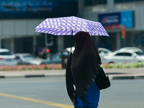 A resident covers herself from the sun on a hot summer afternoon in Dubai.