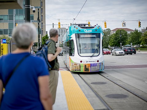 Travels wait as a newly constructed QLine streetcar arrives at a Woodward Avenue light rail station in Detroit, Michigan, U.S., on Thursday, June 22, 2017. To lure more young talent straight out of school, Detroit is giving itself a full-on Silicon Valley makeover. General Motors Co. is spending $1 billion renovating its 60-year-old Tech Center in a northern suburb. Photographer: Anthony Lanzilote/Bloomberg