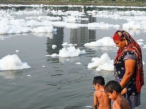 A woman watches as her two boys take a bath in the polluted Yamuna river in New Delhi.