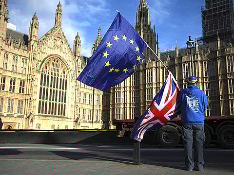 AA man holds the EU and UK flags outside the Houses of Parliament, in central London
