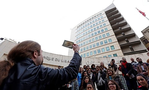 Protesters hold old Lebanese currency near Lebanon's Central Bank building in Beirut.