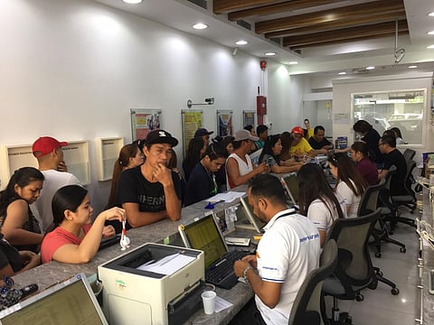 RECOVERY | File photo shows overseas Filipino workers (OFWs) at a remittance centre in Satwa, Dubai.