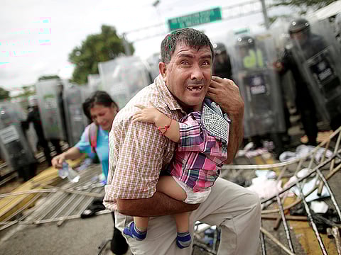 A Honduran migrant attempts to protects his child at a border checkpoint during clashes in Guatemala (File)