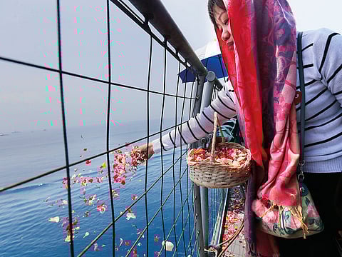 A relative sprinkles flowers during a prayer for the victims of the crashed Lion Air flight 610 on board of Indonesia Navy ship KRI Banda Aceh in the waters where the airplane is believed to have crashed.