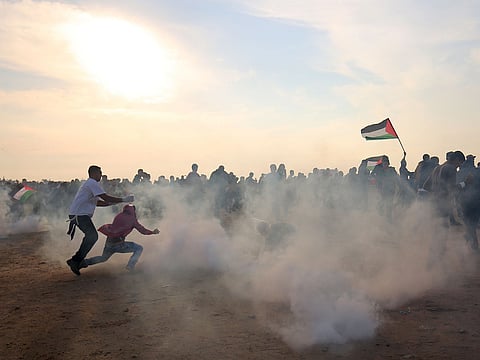 Palestinians run for cover from tear gas during clashes near the border between Israel and Khan Yunis in the southern Gaza Strip on November 9, 2018.