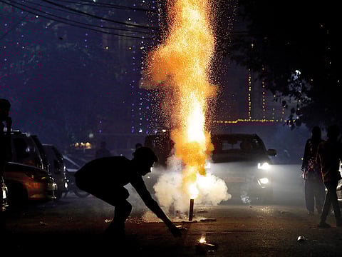 A boy lights a firecracker on a street as he celebrates Diwali in New Delhi.