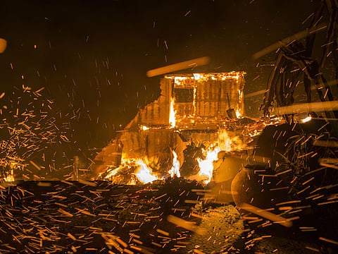 Strong winds blow embers from burning houses during the Woolsey Fire on November 9, 2018 in Malibu, California. After a experiencing a mass shooting, residents of Thousand Oaks are threatened by the ignition of two nearby dangerous wildfires, including the Woolsey Fire which has reached the Pacific Coast at Malibu.
