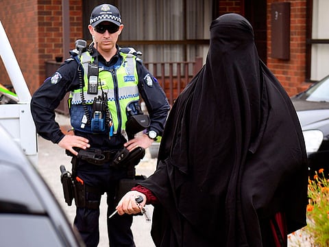 Police stand guard as a woman leaves a house raided by police in the Melbourne suburb of Dallas on November 20, 2018
