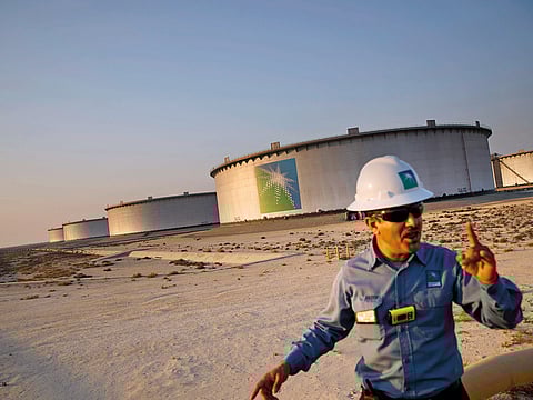 An employee walks past crude oil storage tanks at the Juaymah Tank Farm in Saudi Aramco's Ras Tanura oil refinery and oil terminal in Ras Tanura, Saudi Arabia.