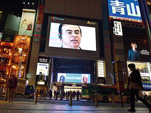 A pedestrian walks past a screen showing a news programme featuring Nissan chairman Carlos Ghosn in Tokyo on November 22.