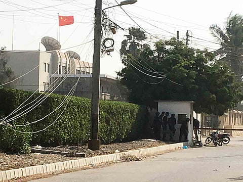 Paramilitary forces and police take cover behind a wall during an attack on the Chinese consulate, where blasts and shots are heard, in Karachi, Pakistan November 23, 2018.