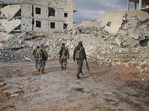Syrian rebel-fighters from the National Liberation Front (NLF) inspect the rubble of a building destroyed by a reported air strike in the rebel-held al-Rashidin district of western Aleppo's countryside near Idlib province