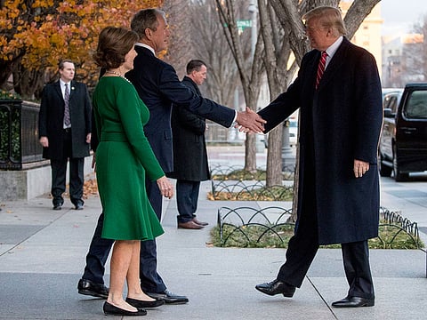 President Donald Trump, right, is greeted by former President George Bush and former first lady Laura Bush outside the Blair House across the street from the White House in Washington, Tuesday, Dec. 4, 2018