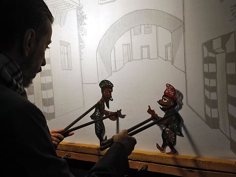 Syrian last shadow puppeteer Shadi al-Hallaq is seen moving his puppets Karakoz (R) and Eiwaz (L) from inside his booth during a presentation in Damascus on December 3, 2018.