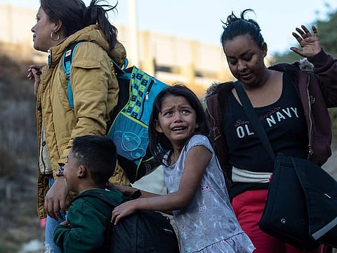 A girl cries as a group of Central American migrants surrender to US Border Patrol agents after jumping over the metal barrier separating Playas de Tijuana in Mexico from the United States, on December 2, 2018, as seen from Playas de Tijuana.