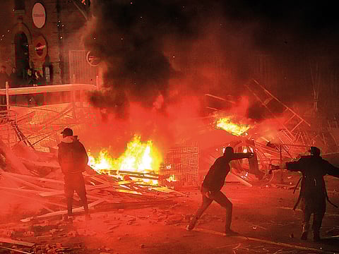 Protestors throw projectiles in a burning barricade during a demonstration of yellow vests (gilets jaunes) against rising costs of living they blame on high taxes in Toulouse, southern France.