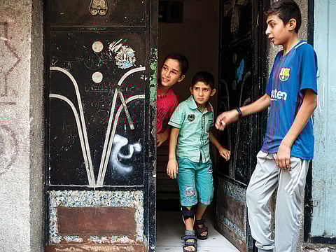 Mohammad Al Dalo, 8 (centre), who was shot in the leg during a demonstration, stands at the entrance of his house in Gaza City. Since March, UN figures show that 948 children under 18 have been shot by Israeli forces and 2,295 have been hospitalised.