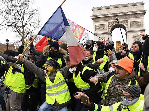 Protestors wearing "yellow vest" (gilet jaune) gesture on December 8, 2018 near the Arc de Triomphe in Paris
