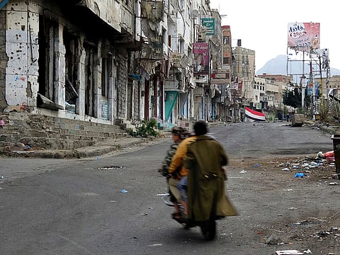 Men ride through streets wrecked by fighting in Taiz, Yemen