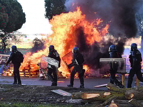 Mobile gendarmes walk next to burning tyres as they try to remove a blockade of "Yellow Vests" protesters demonstrating against rising oil prices and living costs