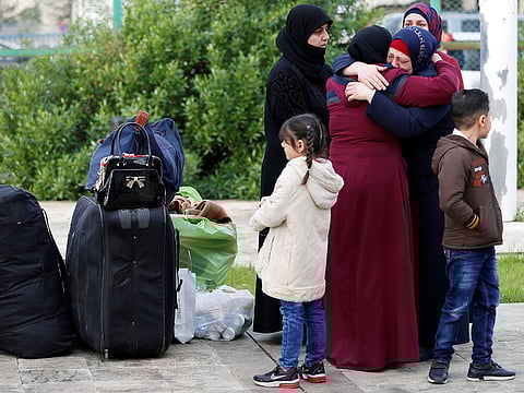 A Syrian refugee girl stands near luggage of Syrian refugees returning to Syria, in Beirut, Lebanon