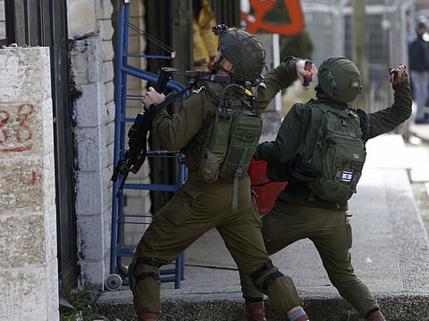Israeli soldiers throw sound bombs as they clash with Palestinians during a search for suspects in the West Bank City of Ramallah in a file photo.