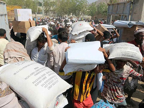 Internally displaced people carry food aid they received, from an ICRC aid distribution centre, in Bajil, Yemen