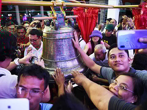 Residents take photos and try to touch one of the three Balangiga church bells after a ceremony returning them to the church in Balangiga in Eastern Samar province on December 15, 2018.