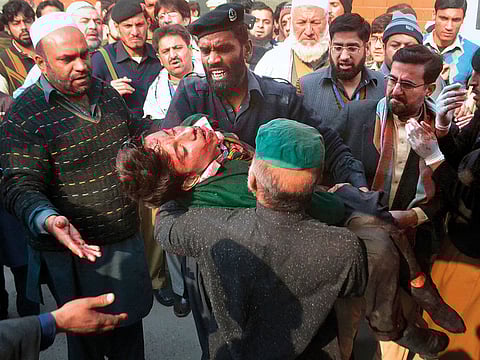 Hospital security guards carry injured students after the attack on the Army Public School in Peshawar on December 16, 2014.