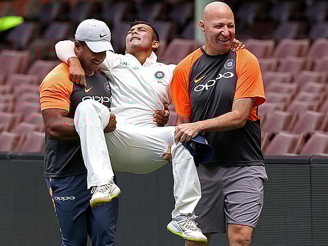 India's Prithvi Shaw, center, is carried by support staff after rolling his ankle while attempting a catch during their tour cricket match against Cricket Australia XI in Sydney